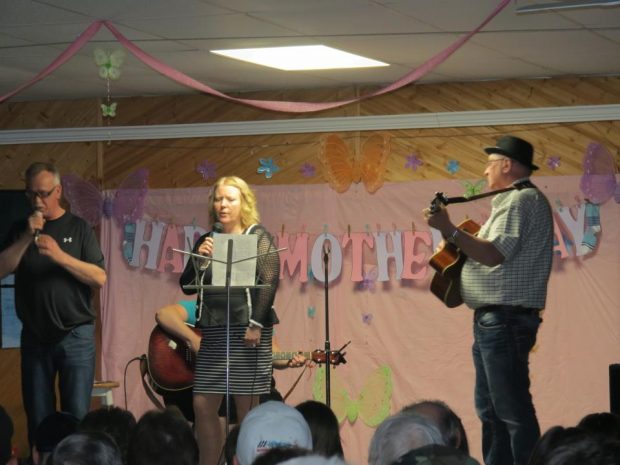 A man and a woman sing on stage accompanied by a guitarist at a concert