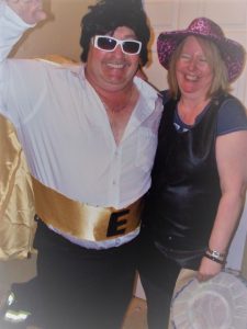 A man dressed as Elvis and a woman prepare for a concert