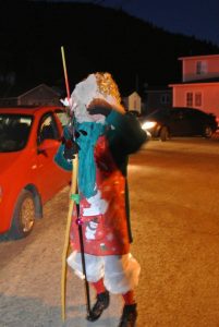 One mummer walks outside with a stick in a night time mummers parade