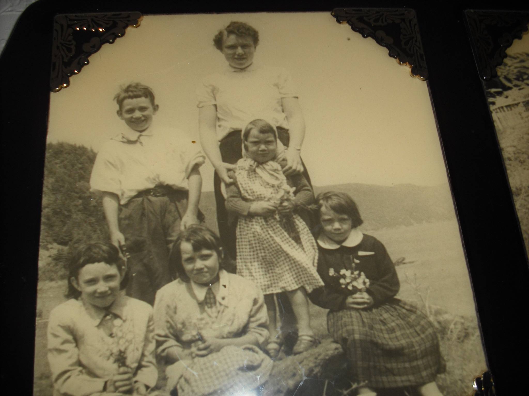 A black and white picture picture shows a woman and five children dressed for a special occasion. The children hold wildflowers in their hands