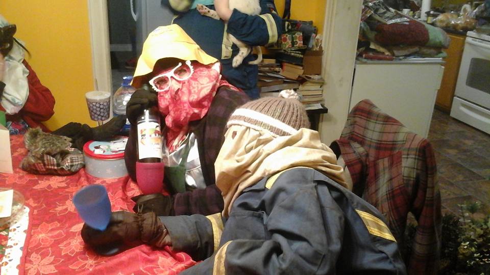 two people with covered faces and dressed as mummers sit at a kitchen table