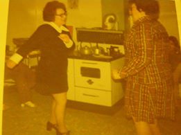 Two women dance a step dance in a kitchen