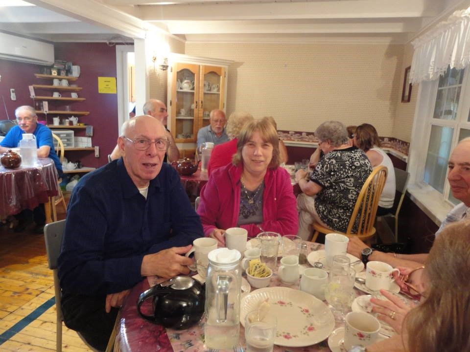 Frank and Ann Murphy sit together at a table at a Seniors' Time. Other seniors are visible in the background