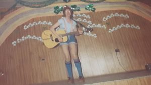 a woman dressed up in short pants plays a guitar on stage