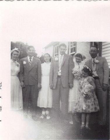 A bridal party stands outside a community hall