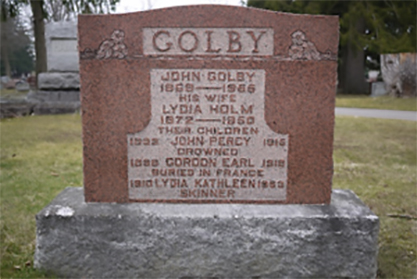 A rectangular stone grave with ornaments at the top and the word GOLBY.