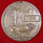 A circular brass plaque with the image of a women holding laurel leaves and a lion in front of her.