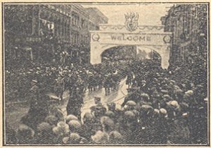 Crowds cheer soldiers passing under an arch.