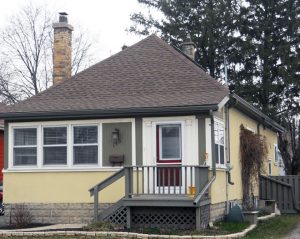 Une maison à un étage pourvue d’un petit porche situé à la gauche de l’édifice en guise d’entrée principale.