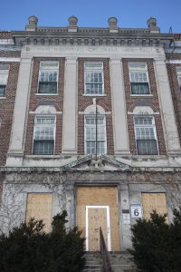 Photograph of a building façade, 3 storeys, in red brick, a set of 3 windows on 2nd and 3rd floor. A stair leading to the entrance can be seen. The entry doors are covered in plywood. The inscription "War Memorial Children's Hospital” is engraved at the top.