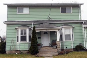 une maison à 2 étages avec une porte d'entrée au centre, située en haut de 4 marches d'escalier.