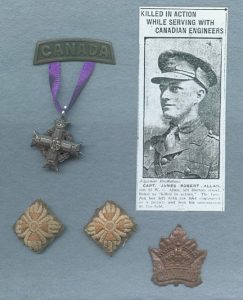 Une croix grecque en argent suspendue à une plaque en métal par un ruban pourpre. Deux petites broderies en forme de losange (pips) et une feuille d’érable en cuivre avec une couronne et le mot CANADA. En haut à droite, la photo d’un soldat portant une casquette.