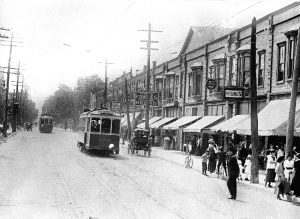 Une rue dans une ville, avec des tramways, des personnes et des bâtiments.