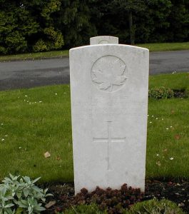 A grave stone with a cross and a maple leaf.