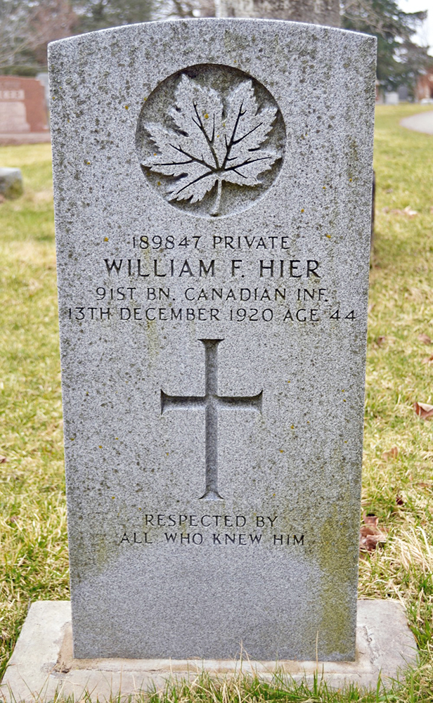 A grave stone with a cross and a maple leaf carved in.