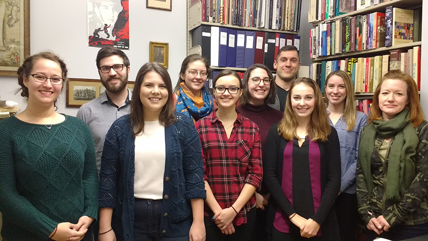 Nine students and their teacher in front of bookcases.