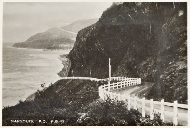 Photograph showing the winding Boulevard Perron in the municipality of Marsoui. Perron Boulevard crosses a rocky cape and is bordered by a white painted wooden fence.