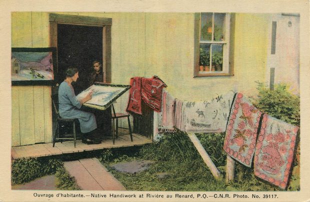 Post card. Hand-painted photography. A woman is sitting on the porch of a house. She paints a winter scene on a canvas whose base is resting on her lap. Near her, six handmade carpets are placed on a fence and a frame, a winter scene is hung on the outside wall of the house. In the opening of the door, a young boy watches his mother stitching a carpet.