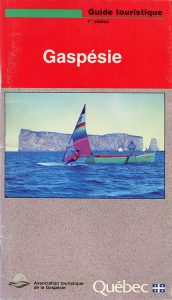 Cover of the first edition of the tourist guide of the Gaspésie region. In the center of the page is a photograph of a fisherman standing in a fishing boat and a man practicing the sport of windsurfing. In the background Percé Rock looms large.