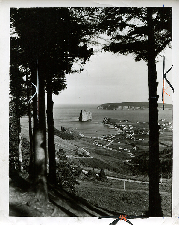 Black and white photography of Rocher Percé. This is one of the most popular viewpoints. The photograph is taken from a high point, at a distance from the Rock, giving a view of the village of Percé, Bonaventure Island and Rocher Percé. The trees on both sides of the photographs create a natural frame of the landscape.