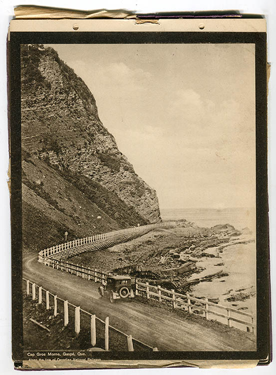 Sepia photograph of a car on the Boulevard Perron consisting of a gravel road winding at the foot of a huge rocky cape in the narrow passage between the cliff and the sea. A simple wooden fence separates the road from the shoreline