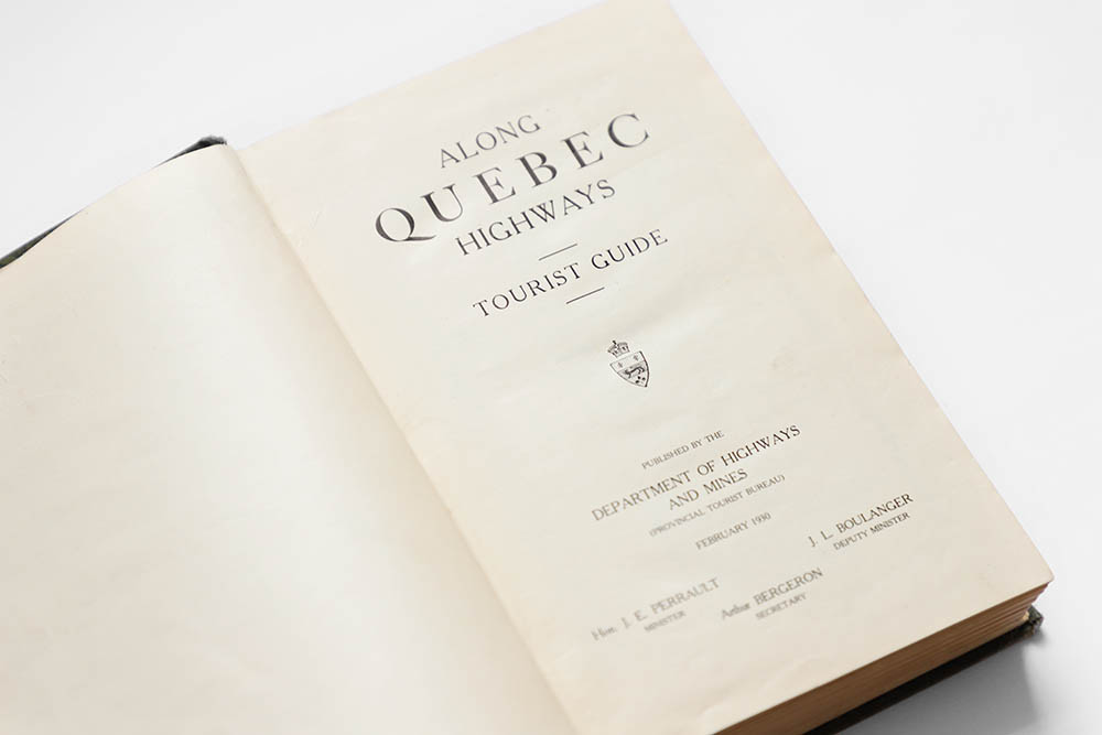 Photographie couleur de la page titre du guide touristique Along Quebec Highway. Il est écrit: Along Quebec Highway Tourist Guide. Published by the department of highways and mines (provincial tourist bureau) février 1930. Et les noms des responsables: le ministre J. E. Perrault, le vice-ministre J. L. Boulanger et le secrétaire Arthur Bergeron. 