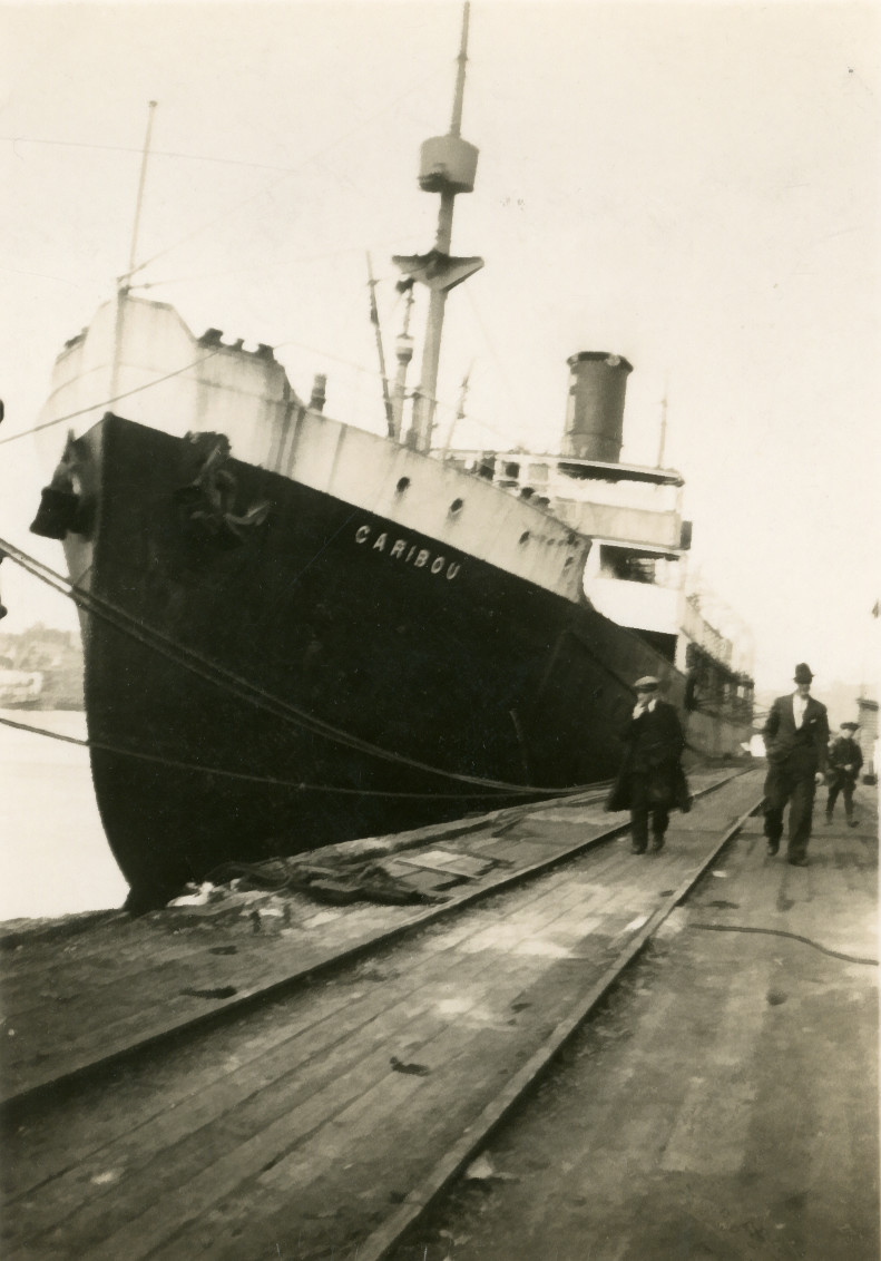 Steamship tied to a wharf where two men and a boy are walking