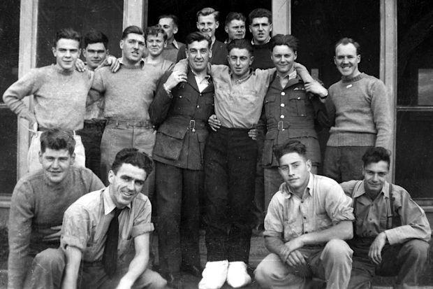 Group of 16 young men standing outside a building