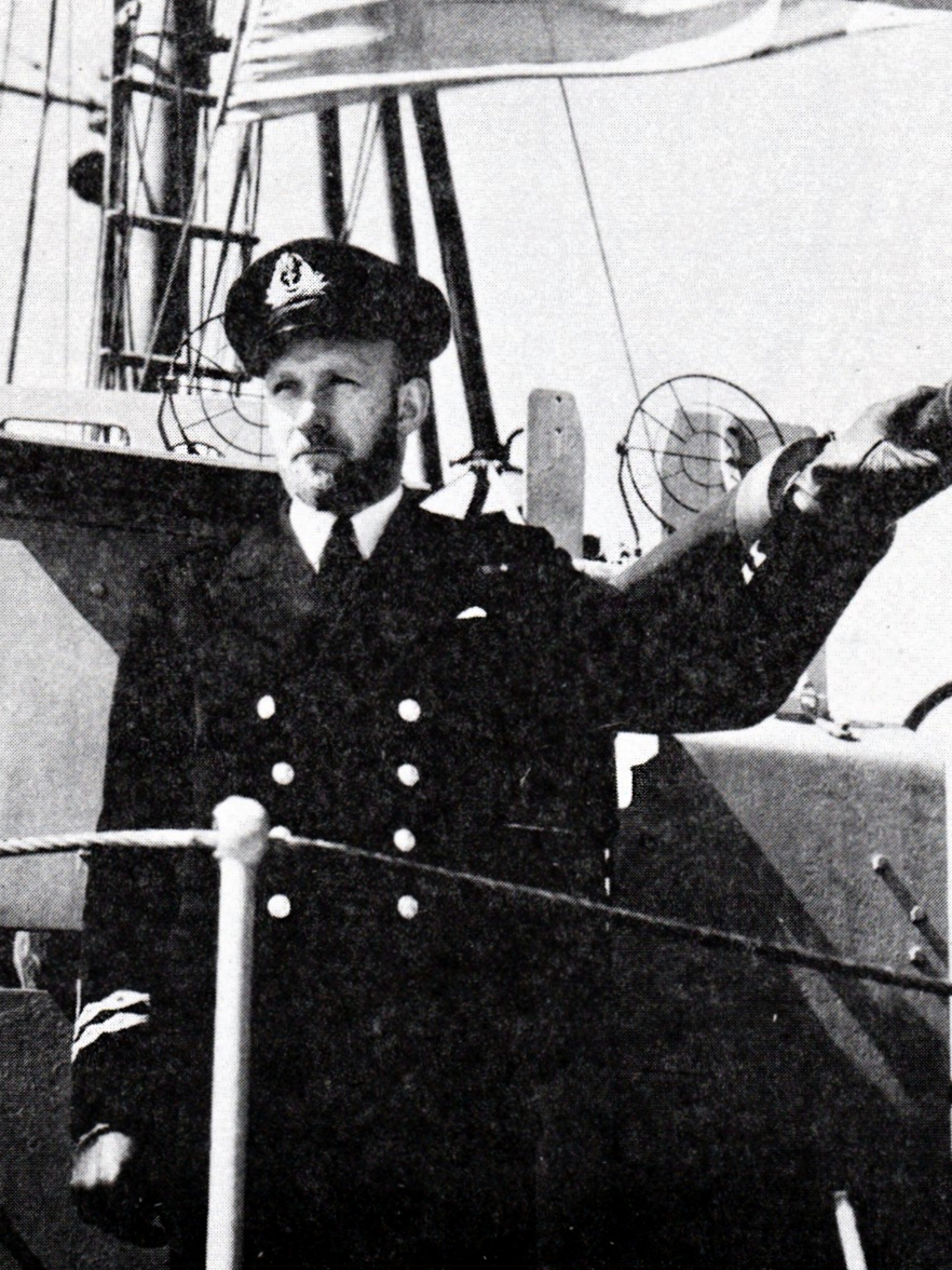 Navy officer standing beside deck gun on warship
