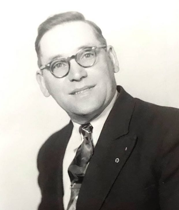 John Dominie pictured wearing glasses, a suit and tie
