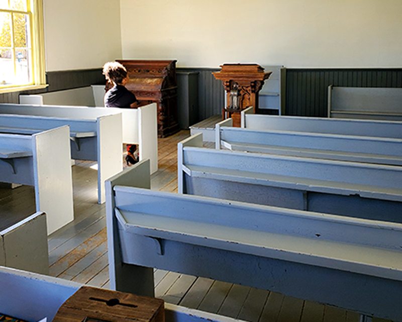 Gabriela seated in a wooden pew inside the historic church at the Josiah Henson Museum in Dresden.