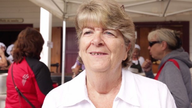 Bust shot of Francine Racette with short blonde hair, wearing a white shirt, standing outside under a tent.