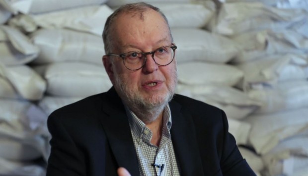 Bust shot of Jacques Lecours with a white beard and round glasses, wearing a black jacket.