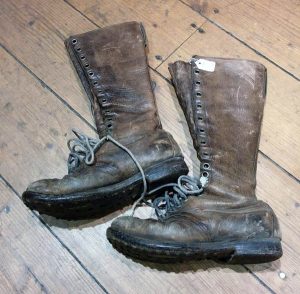 Knee-high brown boots with studded sole, faded leather, and several lacing holes.