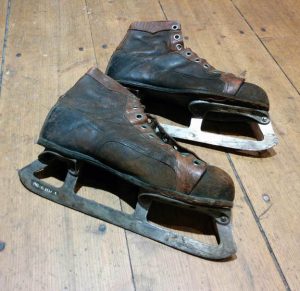 Coloured picture of a brown and black pair of ice skates, faded leather.
