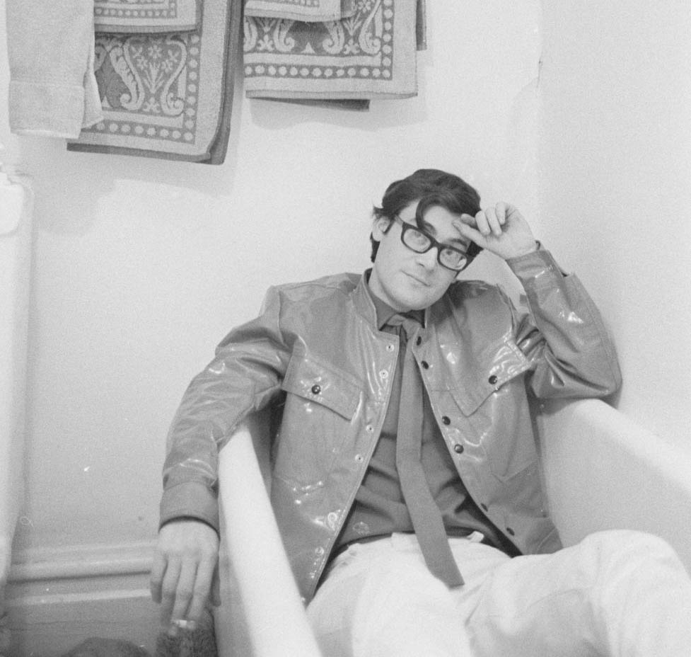 Black and white picture of a man in a suit sitting in a bathtub.