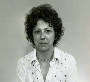 Photographie noir et blanc d'un portait d'une femme aux cheveux frisés, vêtue d'une chemise et d'un collier.