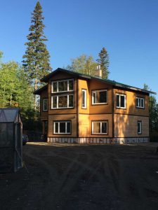 Vue sur une maison nouvellement construite, à deux étages, entourée d'arbres.