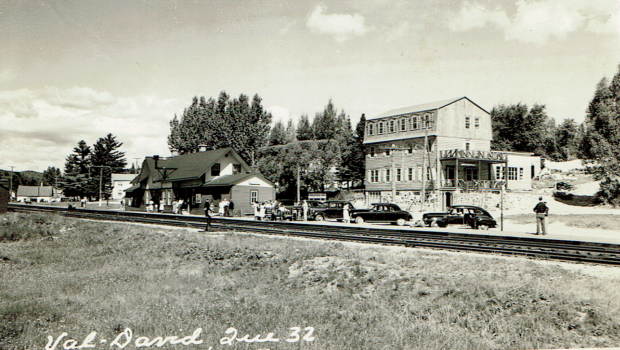 Postcard showing Auberge La belle Chaumière in Val-David, with the railway tracks, Val-David Station and 1940s automobiles.