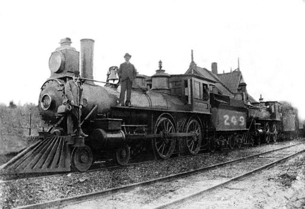 Old photograph of a men standing on the locomotive of the train up North at St-Jérôme Station in 1876.