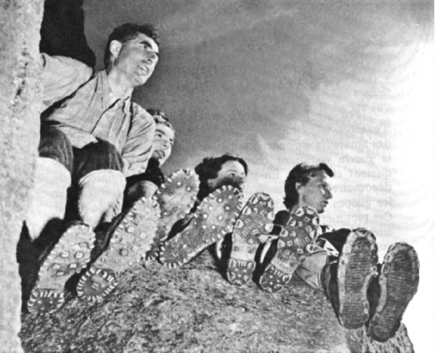 Four people seated on the summit of a rock face.