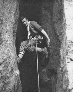 A climber hangs on with feet and hands in a crevasse on a rock face.