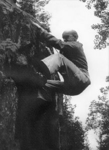 A climber on a rock face in Val-David who, although attached by a rope, does not seem to have any other equipment.
