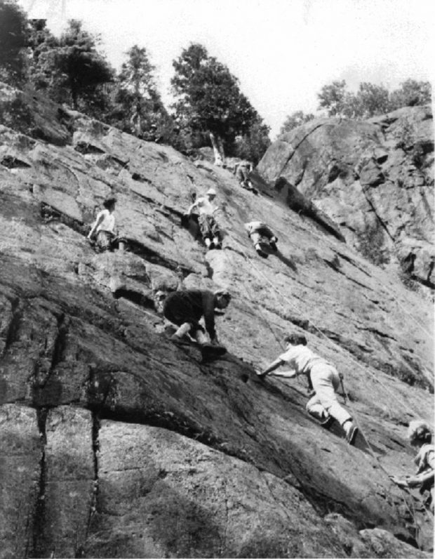 Eight climbers, all attached by ropes, ascending a rock face in Val-David.