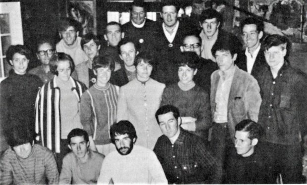 Black and white photo showing a group of about 20 people gathered in a room.
