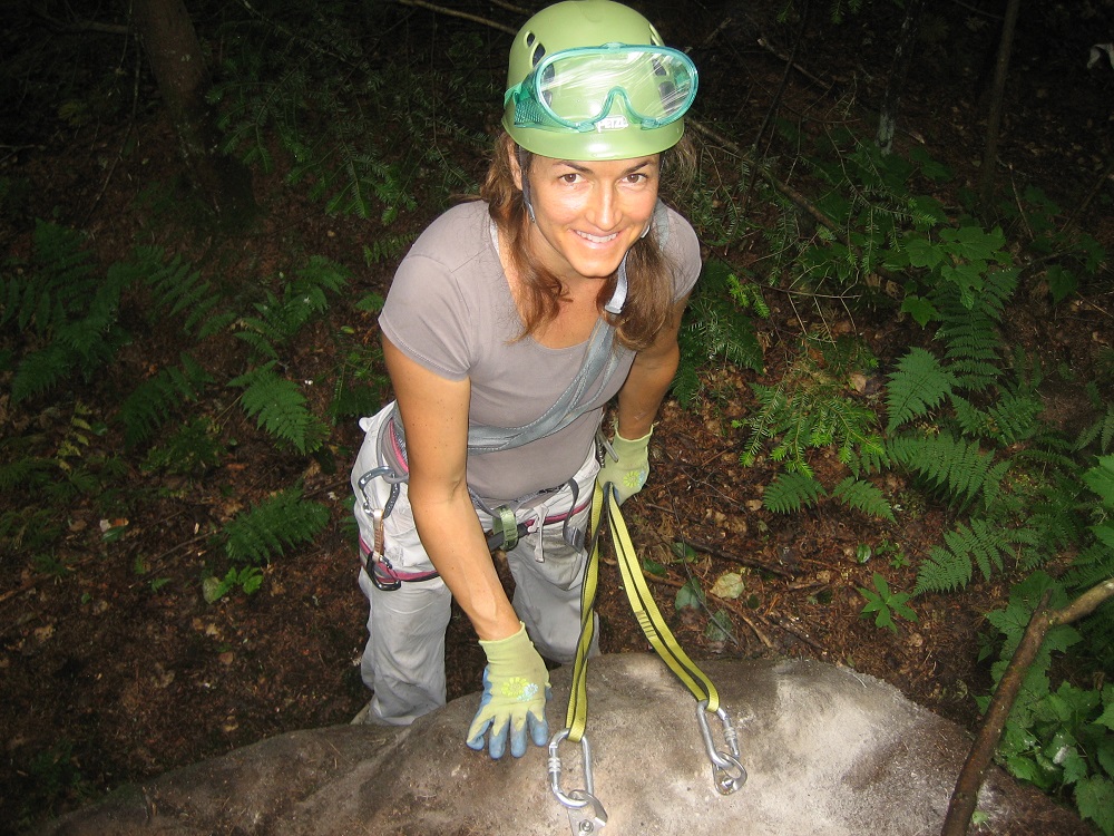 Close-up of a young woman wearing a harness, helmet and safety glasses.