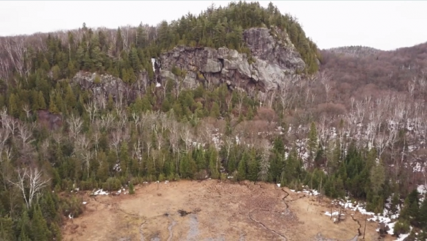 View of a forested mountain in the distance with clearly visible rock walls.