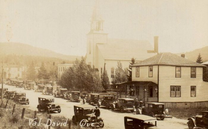 View of the village of Val-David in 1929 showing the main street. the church and old cars.