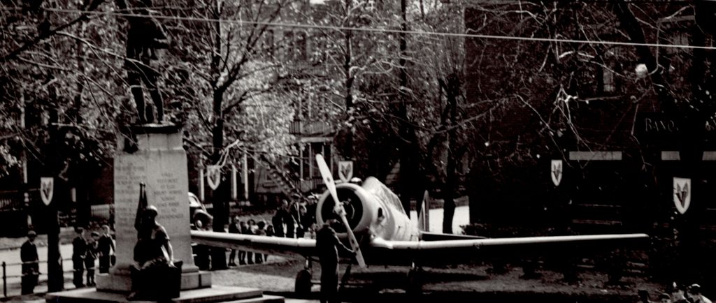 Public park with a statue of a soldier and a military aircraft.