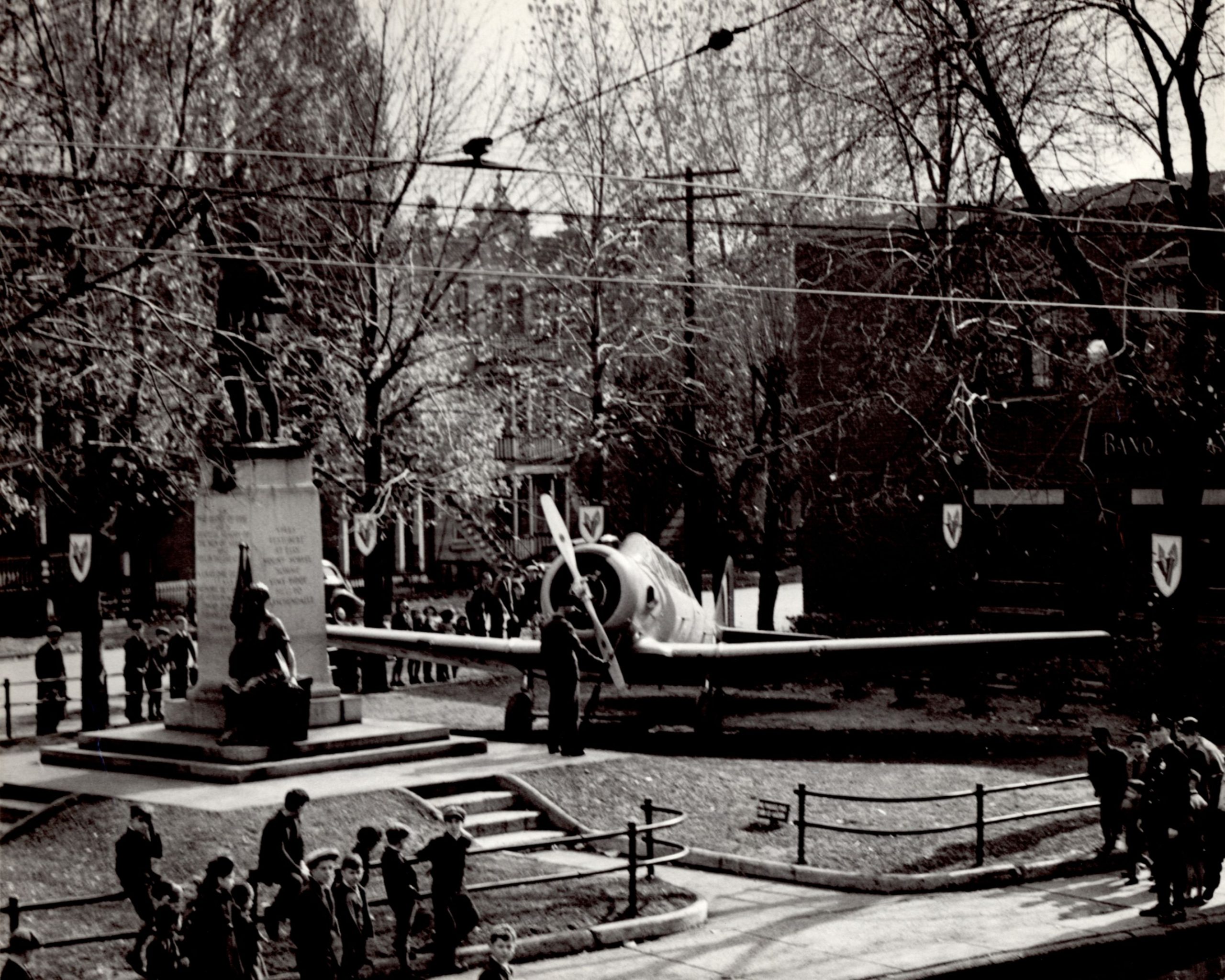 Public park with a statue of a soldier and a military aircraft.